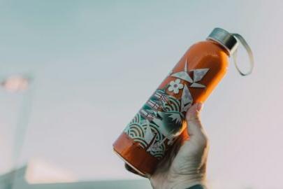 Hand holding an orange flowery water bottle